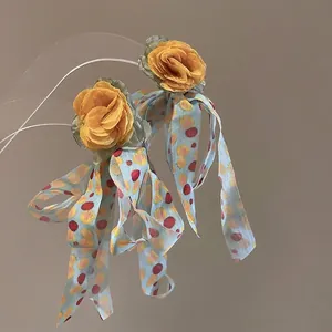 Detailed view of yellow fabric flowers and light blue floral chiffon tassel earrings
