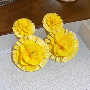Detailed macro view of vibrant yellow flower tassel earrings in a display tray