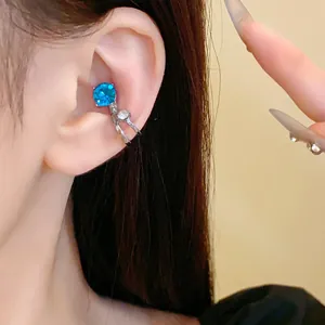 Primo piano di un ear cuff a doppio strato con strass blu brillante e trasparenti.