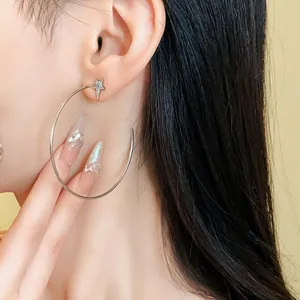 Close-up of elegant silver zircon star hoop earrings worn on ear for a chic style