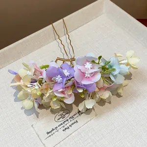 Close-up of elegant floral hair pin with colorful handmade fabric blossoms and gold stick