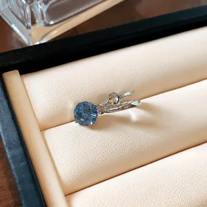 Dettaglio di un ear cuff argento a doppio strato con pietra blu tonda e zircone trasparente.