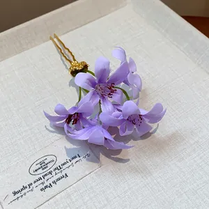 Elegant detail showing soft purple fabric flowers on a gold-toned floral hair fork