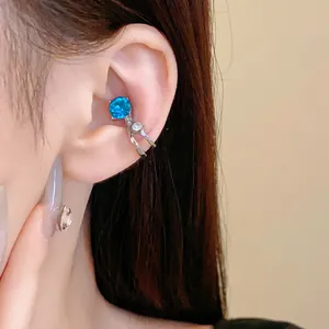 Dettaglio di un ear cuff a doppio strato argentato con una gemma blu brillante