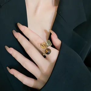 Close-up of chocolate gold plated open ring with square and round zircon stones on finger