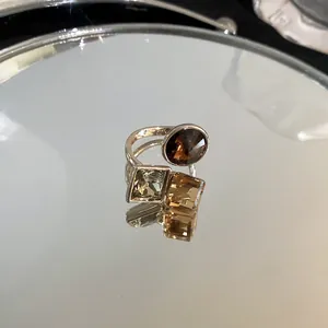 Detailed view of gold-plated ring with square and round zircon crystals on mirror surface
