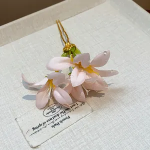 Detailed close-up of a pink fabric flower hair stick featuring elegant dewdrop beads