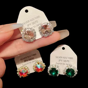 Detail view of luxury zirconia stud earrings in clear, rainbow, and emerald green colors.