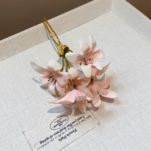 Macro view of a delicate pink fabric flower hair pin on a textured linen background.