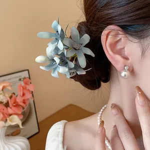 Elegant detail of a sweet blue fabric flower hair pin paired with classic pearl earrings
