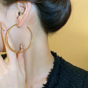 Detailed macro view of a large polished gold hoop earring worn by an Asian model