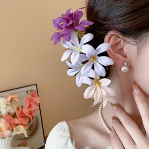 Close-up of elegant fabric flower hair pins in purple and blue on an Asian model.