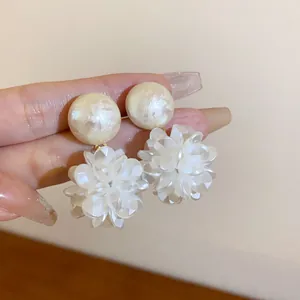 Nahaufnahme von eleganten weißen Blumenohrringen mit runden Perlensteckern und Blüten