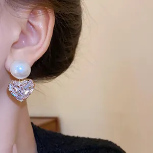 Nahaufnahme eleganter Herz-Ohrringe mit Rundperle und Baguette-Zirkonia