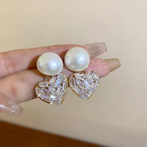 Detailansicht eleganter goldener Perlenohrringe mit schimmernden Kristallherzen