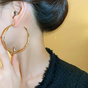 Elegant large gold hoop earrings shown worn on an ear for a stylish fashion look.