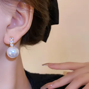 Nahaufnahme eines französischen Perlenohrrings mit Zirkonia am Ohr eines Models