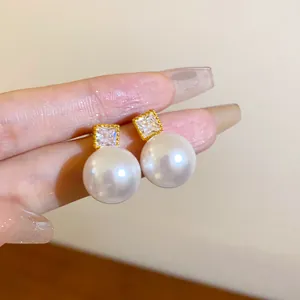 Nahaufnahme von eleganten Perlenohrringen mit quadratischen Zirkonia-Steckern.