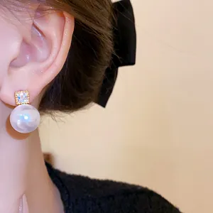 Nahaufnahme eines Models mit eleganten Strass- und großen Perlenohrsteckern am Ohr