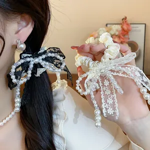 Close-up detail of elegant French lace bow hair scrunchies featuring pearl decorations in black and white.