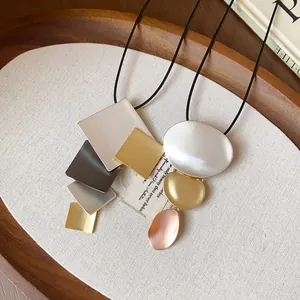 Close-up of geometric metal pendant necklaces with square and oval layered designs