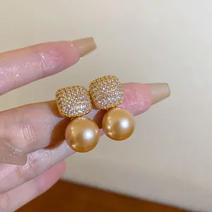Nahaufnahme luxuriöser quadratischer Strass-Ohrstecker mit champagnergoldenen Perlenanhängern