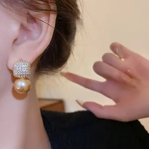 Eleganter goldener Perlenohrring mit pavégefassten Kristallen am Ohr