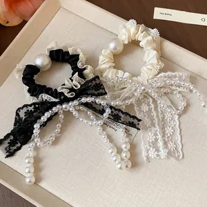 Close-up of French elegant lace bow hair scrunchies with decorative pearl bead strands.