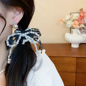 Detail view of a French style lace bow hair tie decorated with elegant white pearls