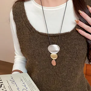 Close-up of geometric metal pendant necklace with silver gold and bronze plating