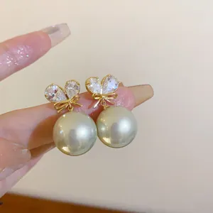 Detailansicht eleganter französischer Herz-Kristall- und Perlenohrringe an Fingern