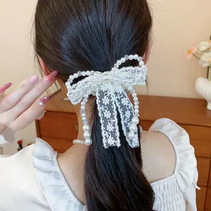 Detail view of an elegant French lace bow hair tie with pearl tassels on a ponytail