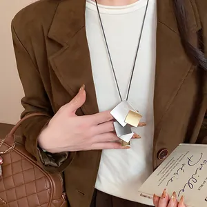 Elegant close-up of a geometric layered metal necklace on a model wearing a brown blazer