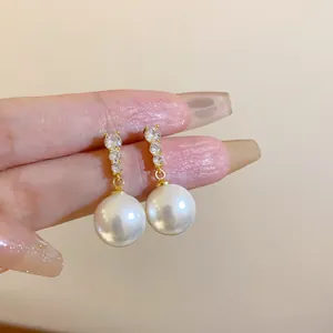Detail von eleganten runden Perlenohrringen mit funkelnden Strasssteinen in der Hand