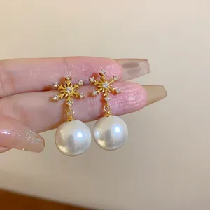 Detailansicht goldener Schneeflocken-Ohrstecker mit eleganten weißen runden Perlen
