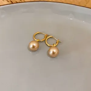 Detailansicht eleganter goldener Creolen mit champagnerfarbenen Perlen