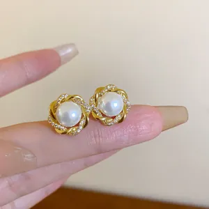 Makroaufnahme der eleganten goldenen Blumenohrstecker mit Perle und Kristallen