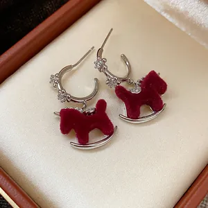 Close-up of silver needle rocking horse earrings with red velvet and crystals.