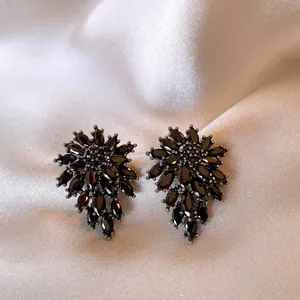 Detailed macro shot of elegant vintage-style black flower stud earrings on silk background