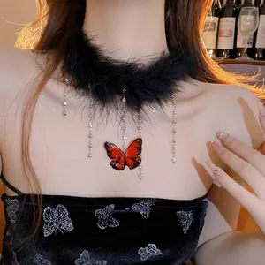 Detail view of a black feather choker with crystal fringe and red butterfly pendant.