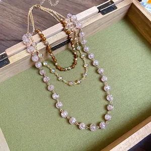 Dettaglio macro della collana multistrato con perle di vetro rosa e catena oro