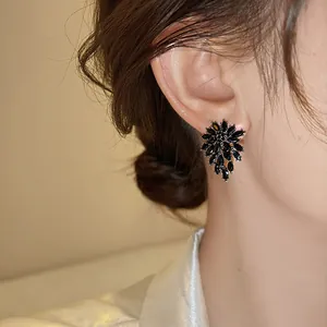 Detail view of elegant black marquise rhinestone flower stud earrings on an ear