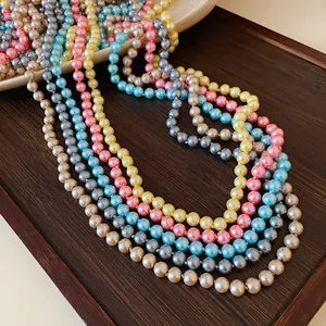 Macro detail of multi-colored long pearl necklaces with elegant luster on a wooden tray