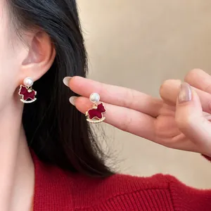Close-up of gold-plated red rocking horse earrings with pearls and zircons on model.