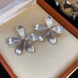 Boucles d'oreilles fleurs argentées avec centre doré dans un écrin de luxe élégant
