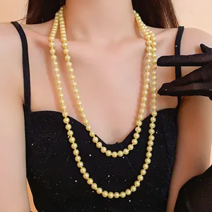 Detail shot of elegant double-strand long pearl necklace on model wearing black dress