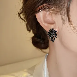 Macro view of elegant black flower crystal stud earrings worn on a female model's ear
