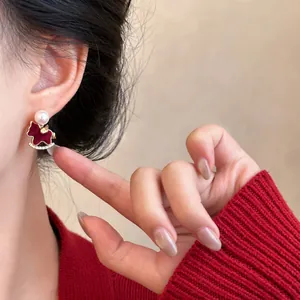 Close-up detail of a red rocking horse earring with a white pearl and zircon accents
