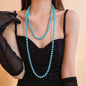 Detailed view of an elegant long blue pearl necklace draped over a black sparkly dress