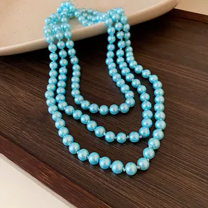 Detailed close-up showing the lustrous light blue pearls of a long layered necklace